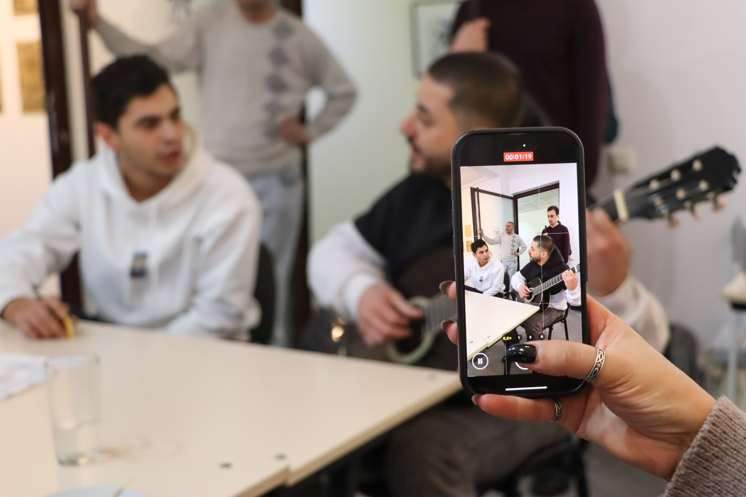 լուսանկարում 2 հոգի են նվագում են կիթառ և երգում նրանք հեռախոսով նկարում են