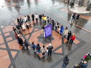 մեծ պոստեռ է, որի շուրջ հրապարակում մարդիկ շրջան են կազմել