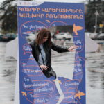 լուսանկարում ֆլեշմոբի մասնակիցներից մեկը պատռում է բռնության պատ խորհրդանշող պոստեռը և դուրս է գալիս