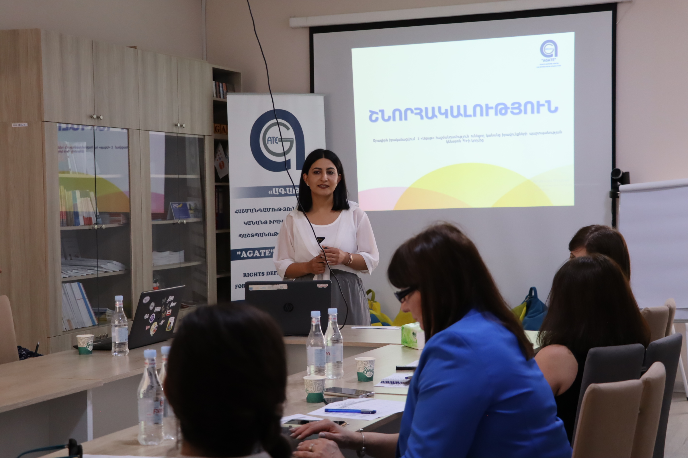 դասընթացավարներից մեկն է դասընթացի ժամանակ, հետևում Ագաթի բաներն է և միացրած է տեսասահիկ